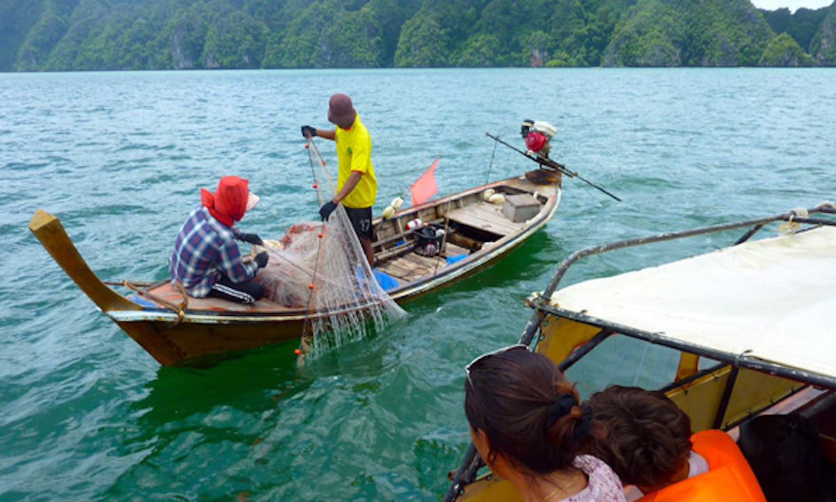 Thai fishermen hauling a net from a longtail boat